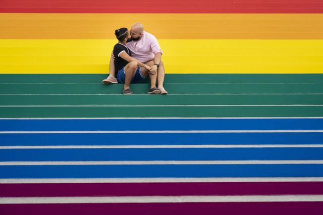 Jesus Tavarez and Juan De La O kiss on the steps that are covered in rainbow colours for Pride Month at Franklin D. Roosevelt Four Freedoms Park in New York City in June.