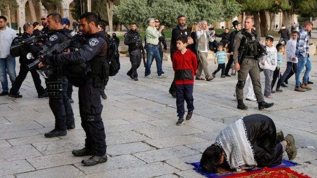 عناصر من قوات الأمن الإسرائيلية يقفون بالقرب من فلسطينيين يصلون في المسجد الأقصى