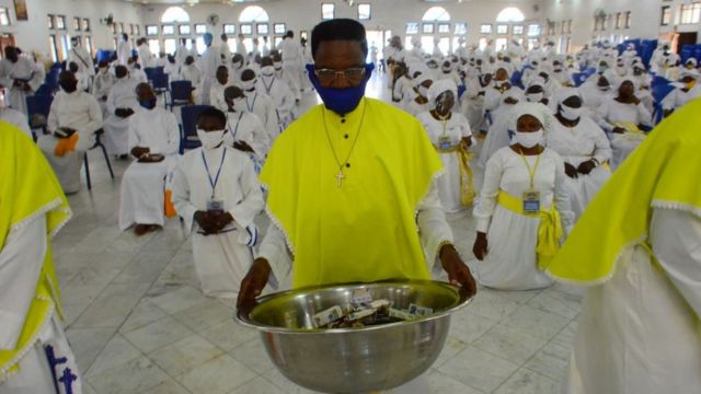 A man wearing facemask carry offering bowl for prayer as worship centers reopen after the COVID-19 lockdown, at the Celestial Church of Christ, Arch Diocese National Headquarter Makoko, Lagos, as measures against the spread of COVID-19 Coronavirus in Lagos, Nigeria on August 8, 2020