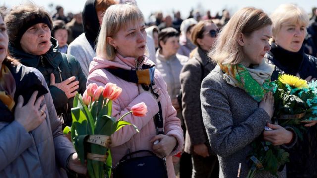 نساء أوكرانيات يغنين النشيد الوطني الأوكراني أثناء دفن الجندي الأوكراني أولكسندر جوشكو في 13 أبريل 2022 في ستاريتشي، أوكرانيا.