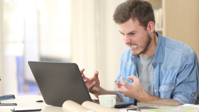 Hombre frustrado y enojado frente a su computadora.
