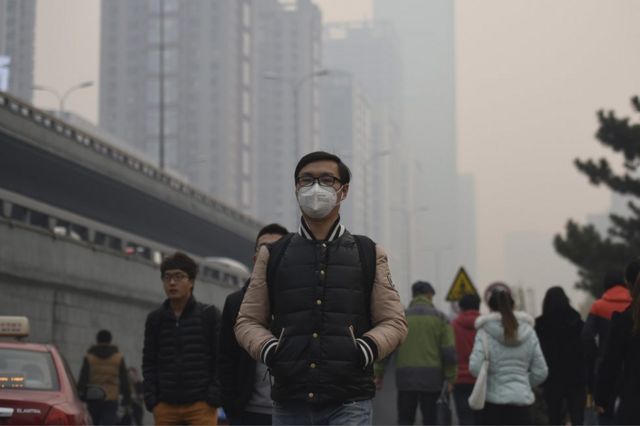 A man wearing a face mask walks along the street on a hazy day in Shenyang in northeastern China's Liaoning province Monday, 9 November 2015.