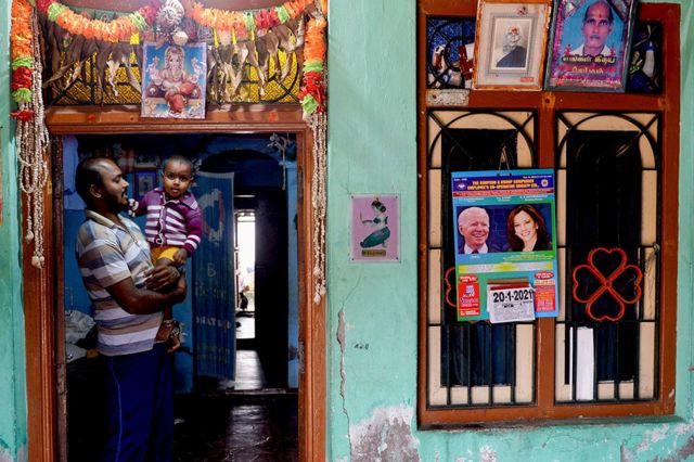 A man stands in this house decorated with a calendar with photos of US President-elect Joe Biden and Vice President-elect Kamala Harris