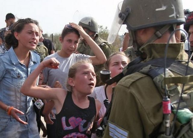 در این عکس عهد تمیمی که ۱۱ سال دارد با مشت گره کرده با سرباز اسرائیلی روبرو می‌شود