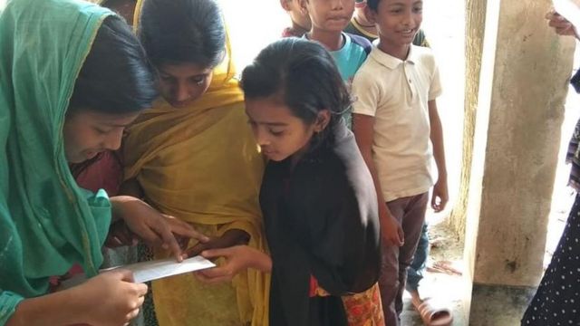 বাংলাদেশের একটি গ্রামে পরীক্ষার ফল দেখছেন শিশু শিক্ষার্থীরা।