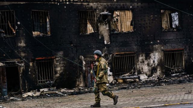 Un soldato ucraino passa davanti a un edificio distrutto a Irbin.