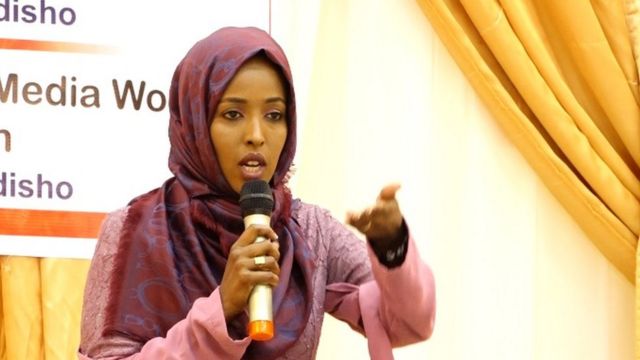 Maryan speaking into a microphone at a conference