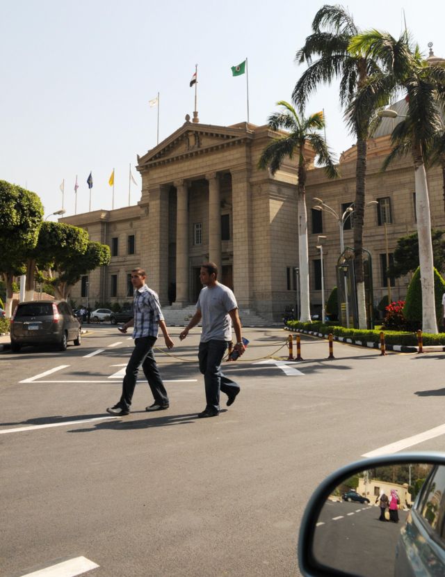 رجلان يمشيان أمام مدخل جامعة القاهرة