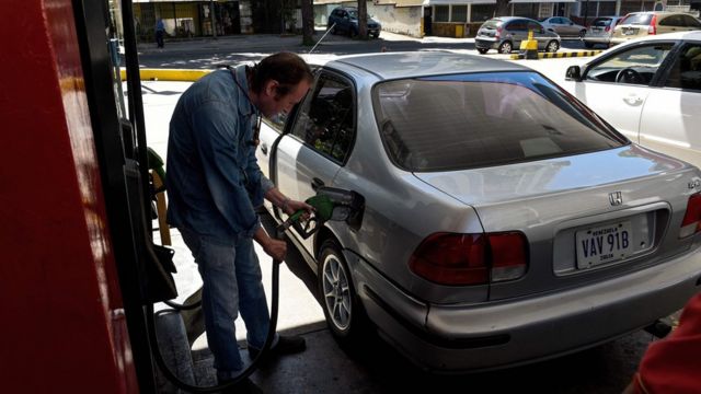 Un hombre llenando el tanque de gasolina de su auto.