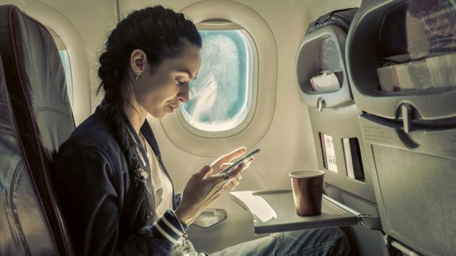 Una persona usando su teléfono para navegar en un vuelo
