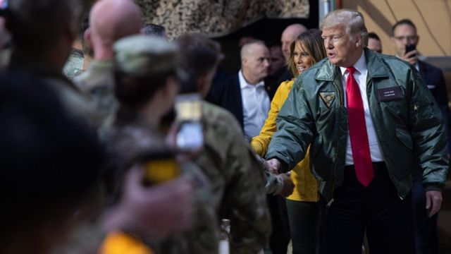 特朗普身穿綠色外衣、佩帶著寫有"三軍統帥"名牌，與駐伊拉克美軍握手。