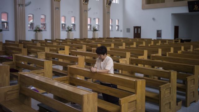 A woman prays alone in a Catholic church in Tianjin. Many Christians in China are part of 'underground' congregations who maintain their independence from state-run churches
