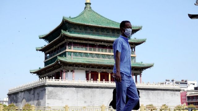 陕西西安一位市民从钟楼前走过（中新社图片6/7/2022）