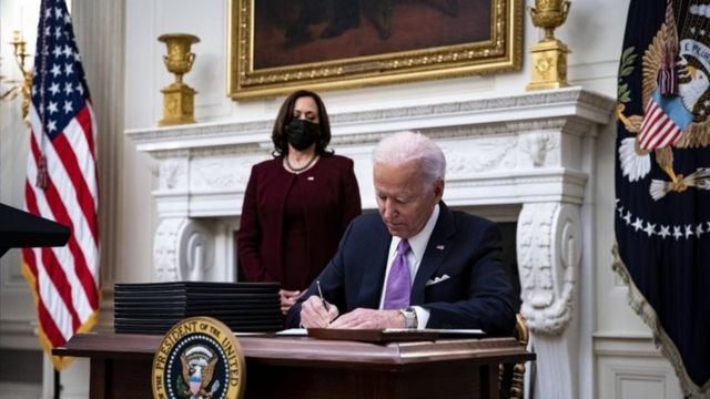 O presidente dos Estados Unidos, Joe Biden, assina uma ordem executiva após falar durante um evento sobre a resposta de seu governo à covid-19, com a vice-presidente dos Estados Unidos, Kamala Harris, à esquerda, na Casa Branca, em Washington DC, nos EUA, em 21 de janeiro de 2021.