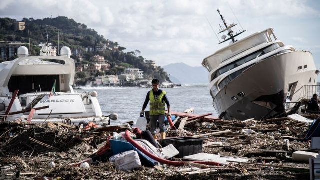 Homem caminha por entre o lixo entre dois íates depois que uma tempestade atingiu a marina durante a noite de 30 de outubro