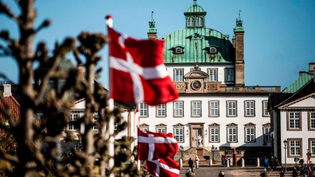 Danish flags flutter in front of Fredensborg Palace in Fredensborg, Denmark, on April 16, 2020