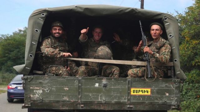 Armenian troops smile sat in the back of a truck