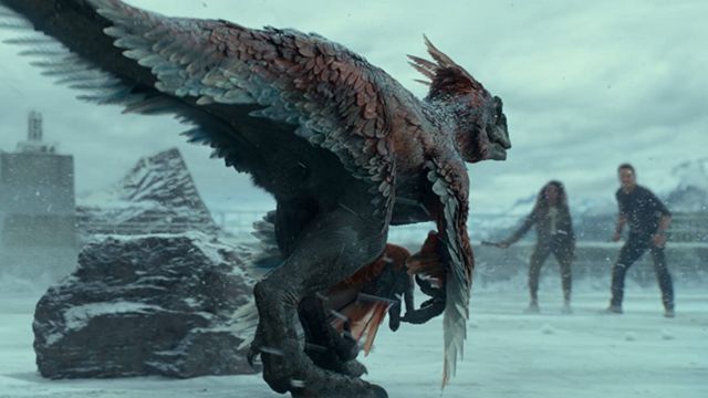 Um dinossauro de cores escuras com penas enfrenta dois humanos