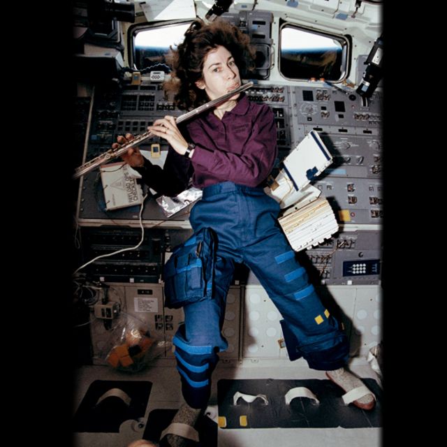 Ellen Ochoa tocando la flauta en el espacio.