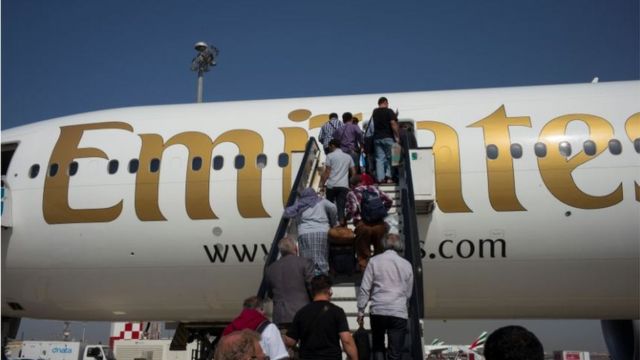 Air passengers climb stairs to an Emirates Airlines Boeing 777 passenger jet departing to Kabul from Dubai