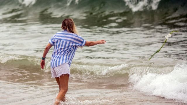 Mulher jogando rosa no mar para Iemanjá