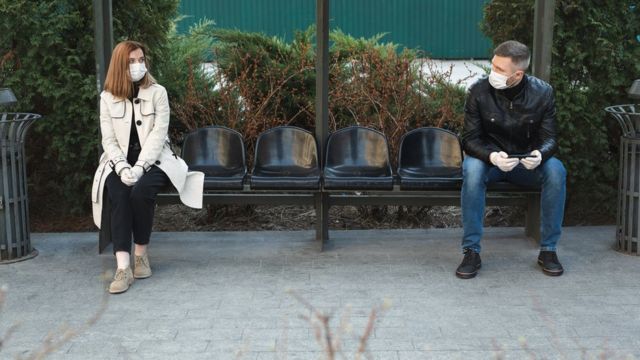 Hombre y mujer sentados a dos metros de distancia.