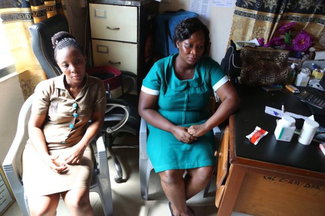 Beatrice Amponfi and Joy Glii sit inside their clinic next to a desk