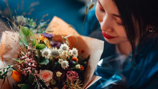 A woman smells a bunch of flowers