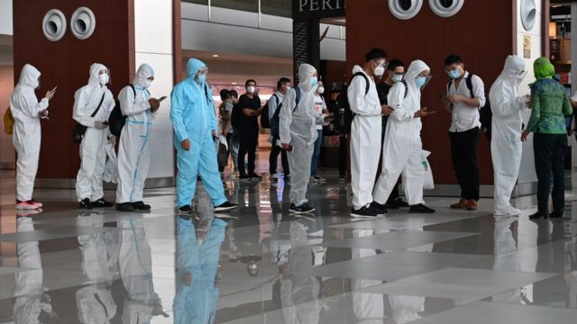 A group of Chinese passengers in medical protective suits at Soekarno-Hatta International Airport in Jakarta, Indonesia prepare to board a flight to Shenzhen (8/6/2021)