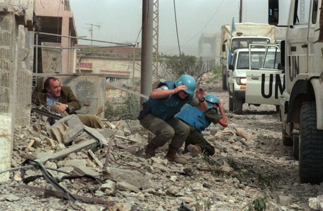 أفراد من اليونيفيل ومصور لوكالة فرانس بريس يحاولون الاحتماء من غارة إسرائيلية استهدفت قافلة للقوات الدولية كانت تساعد في نقل مدنيين إصيبوا في غارة إسرائيلية قرب مدينة صيدا اللبنانية في شهر أبريل/نيسان عام 1995.