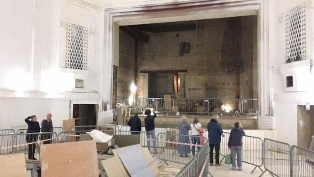 People standing in a cinema room looking at renovation works, in front of a theatre stage