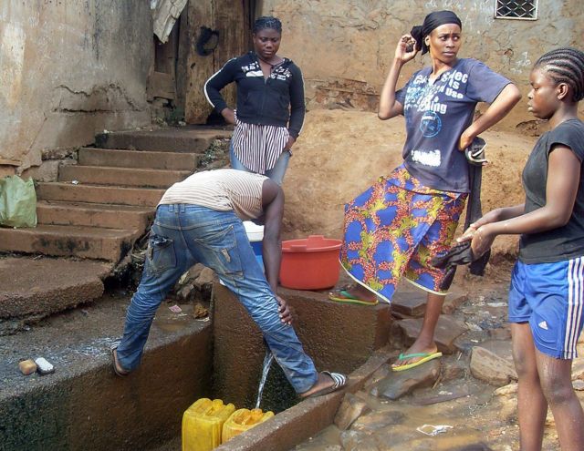 Pessoas em Yaoundé pegando água  de uma fonte