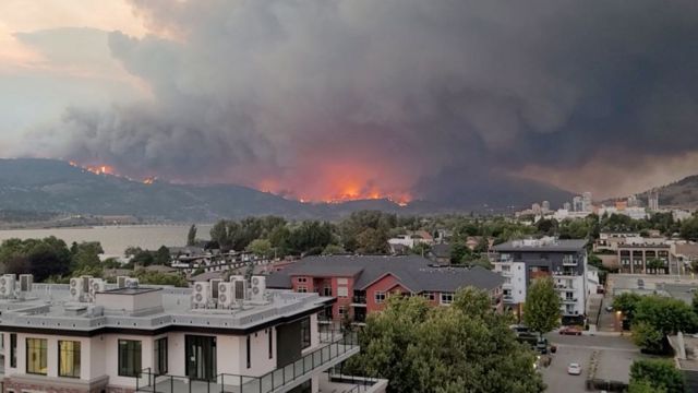 cidade em primeiro plano, com fogo em montanhas ao fundo