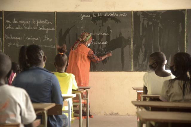 Une enseignante écrit au tableau devant ses élèves