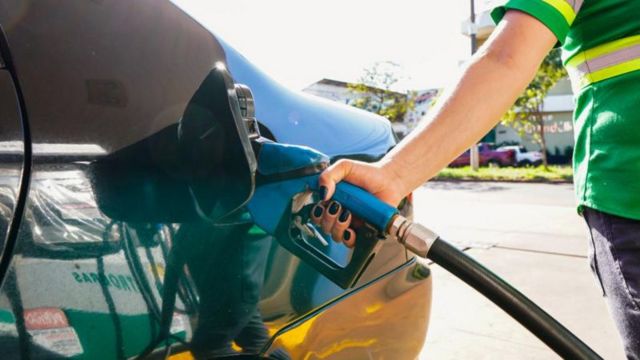 Frentista abastece carro em um posto de gasolina