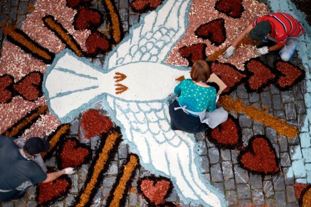 Uma mulher participa da confecção de um tapete de areia e serragem para a procissão católica de Corpus Christi em uma rua de Mariana, a cerca de 120 km de Belo Horizonte, em 31 de maio de 2018