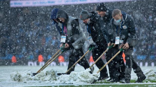 Manchester City ground staff clear the pitch at half-time against West Ham