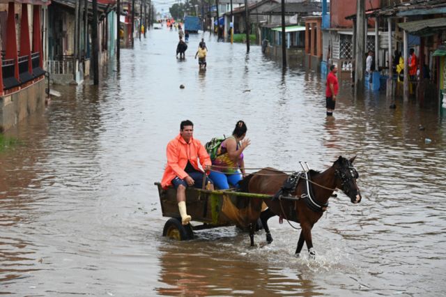 Una pareja viaja en un carruaje tirado por caballos a través de una calle inundada en Batabanó, provincia de Mayabeque, Cuba.