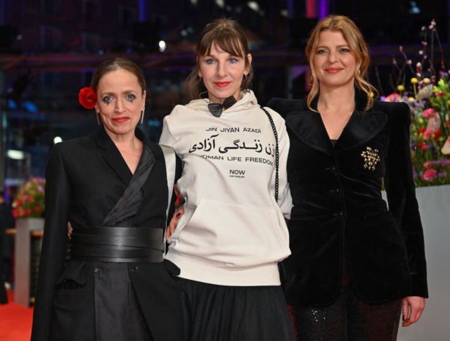 در جشنواره امسال در برلین، مرت بکر (وسط) از بازیگران سینمای آلمان، با لباسی که بر رویش شعار زن، زندگی آزادی نقش بسته بود بر روی فرش قرمز حاضر شد