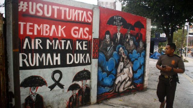 Seorang warga Kota Malang melewati mural menuntut pengusutan tuntas Tragedi Kanjuruhan di Malang.