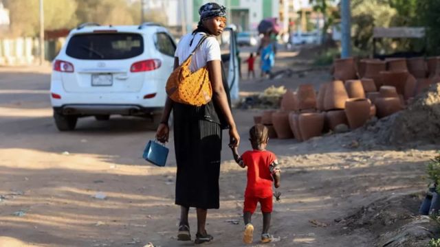 Una mujer y un niño caminan por la capital de Sudán