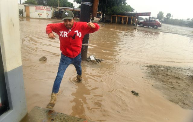 Un peatón evita una calle inundada por la tormenta tropical Hilary en Ensenada, México.