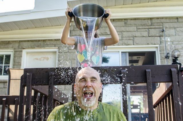 Criança jogando um balde de água na cabeça de um homem adulto