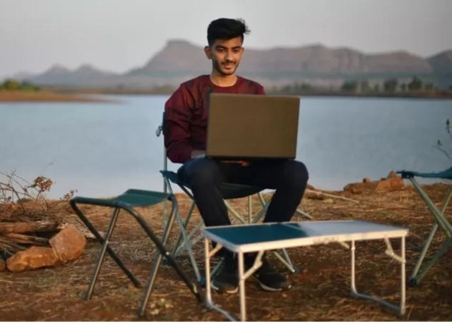 Un homme connecté avec son ordinateur au bord du fleuve