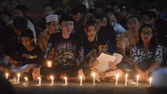 Warga bersama suporter Arema FC (Aremania) berdoa bersama di halaman Stadion Kanjuruhan, Malang, jawa Timur, Minggu (2/10/2022).