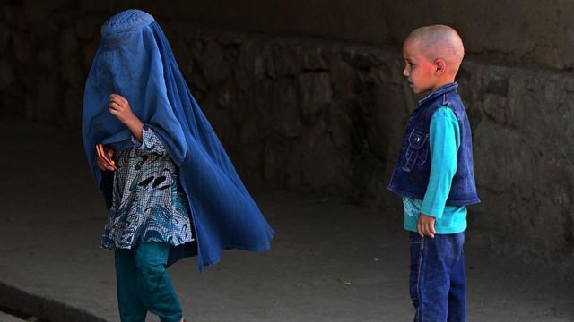 Una niña con una burka y un niño que la mira