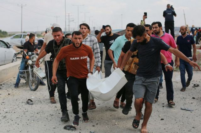 Homens palestinos carregam uma vítima após um ataque aéreo israelense na passagem de Erez entre Israel e o norte da Faixa de Gaza