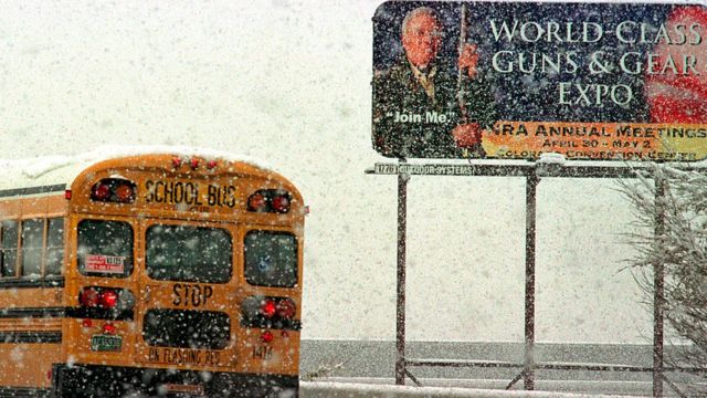 Ônibus escolar passando por um anúncio da NRA
