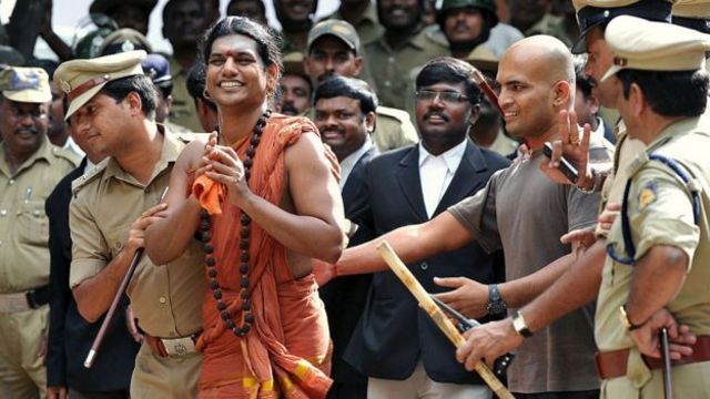 Nithyananda Paramashivam sorrindo enquanto é levado por policiais