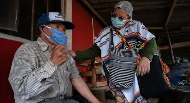 Enfermeira interagindo com homem indígena em Suba, na Colômbia, durante a pandemia